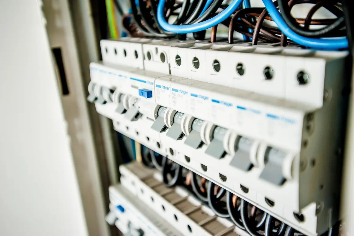 Wnętrze otwartej rozdzielnicy elektrycznej z rzędami wyłączników nadprądowych i podłączonymi przewodami.